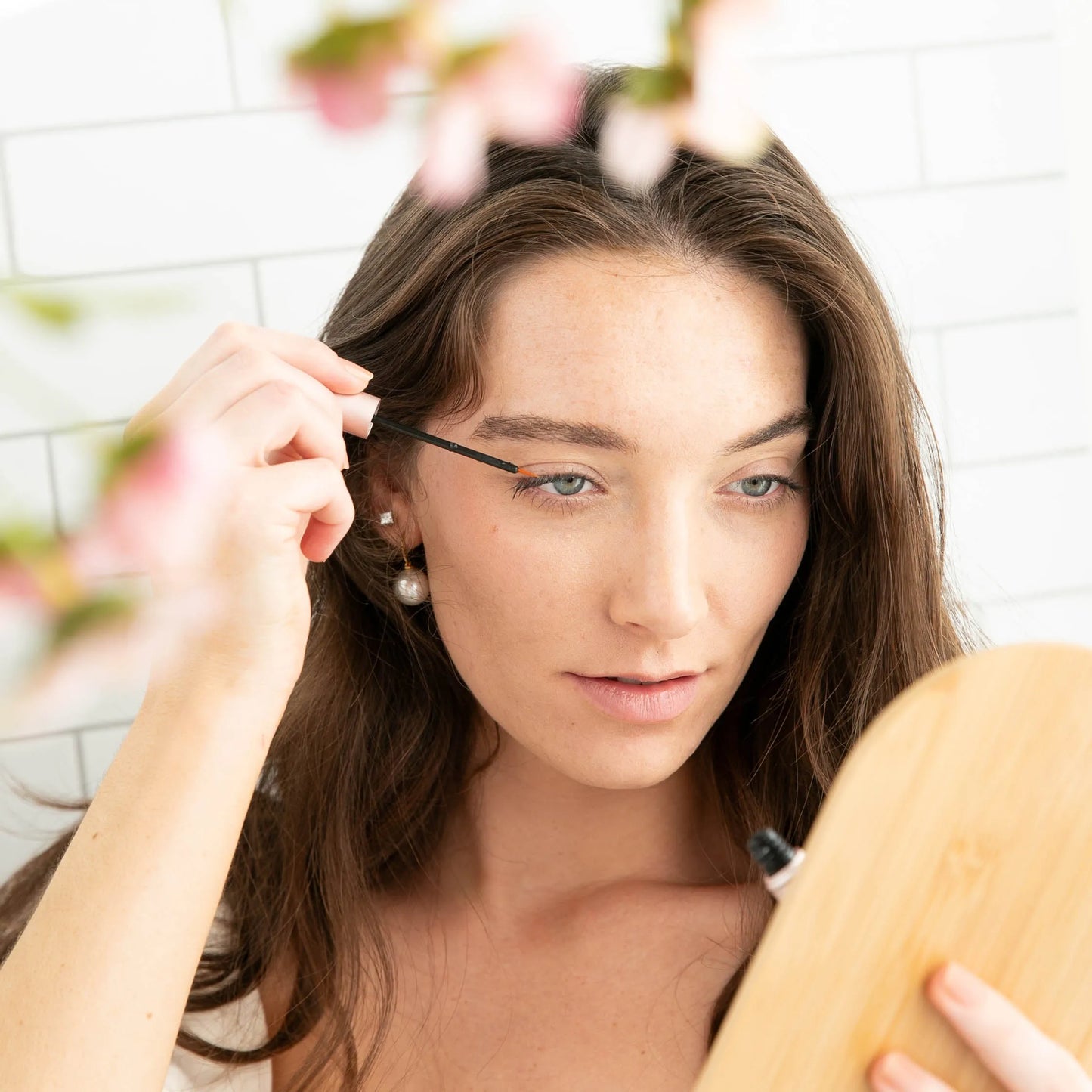 Woman applying MiyLash Travel Eyelash Volumizing Growth Serum with a precise brush, perfect for travel-friendly eyelash care.